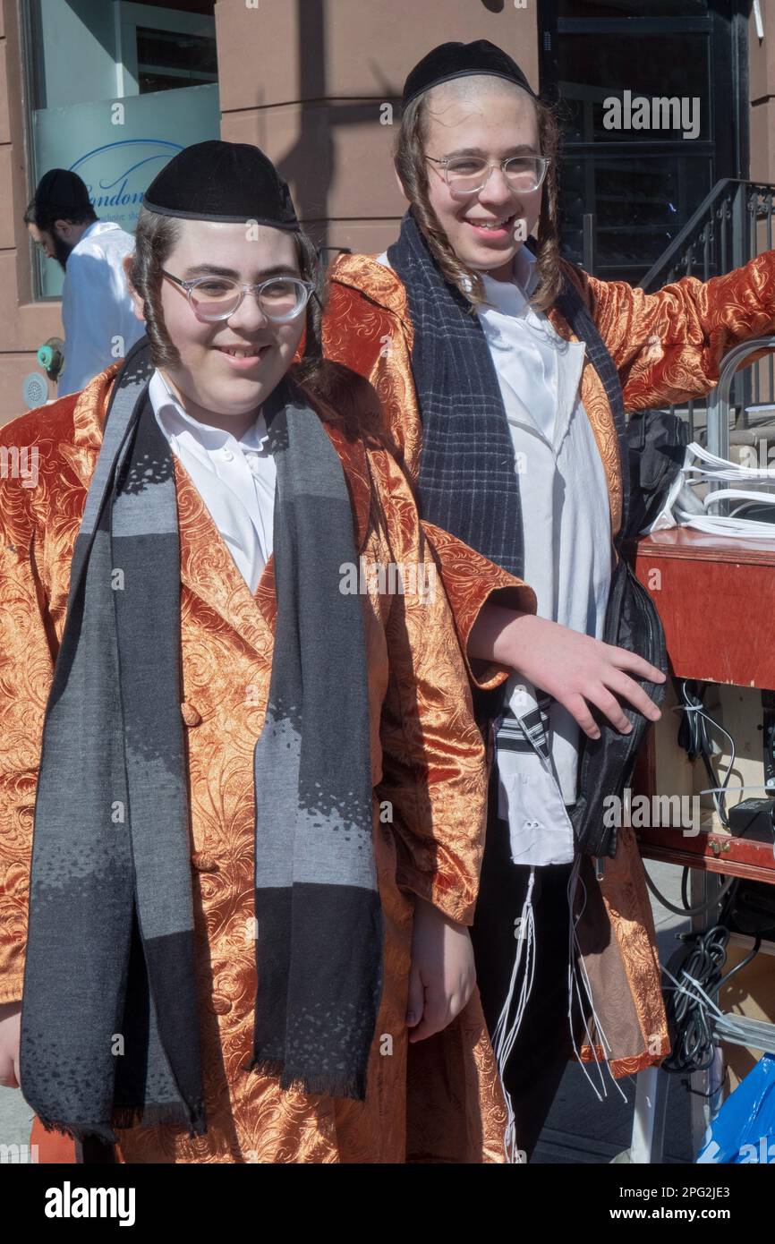 Posiertes Porträt von 2 chassidischen Teenagern in orangefarbenen Mänteln als Purim-Kostüme. In Brooklyn, New York. Stockfoto