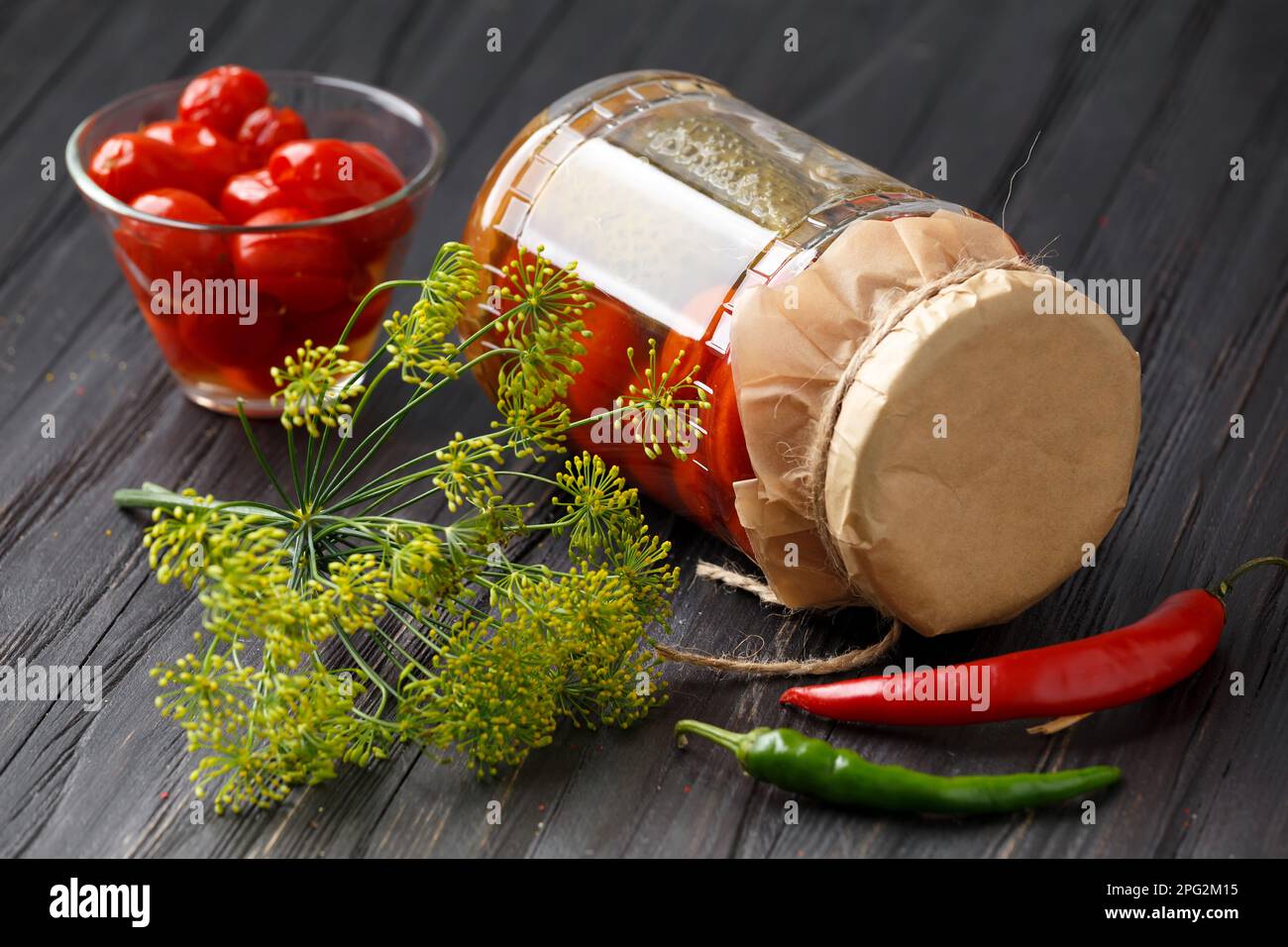 Tomaten in Dosen und Gurken in einem Glas. Marinierte Tomaten in einer Schüssel. Eingelegte Tomaten mit Chili, Dill und Knoblauch. Stockfoto