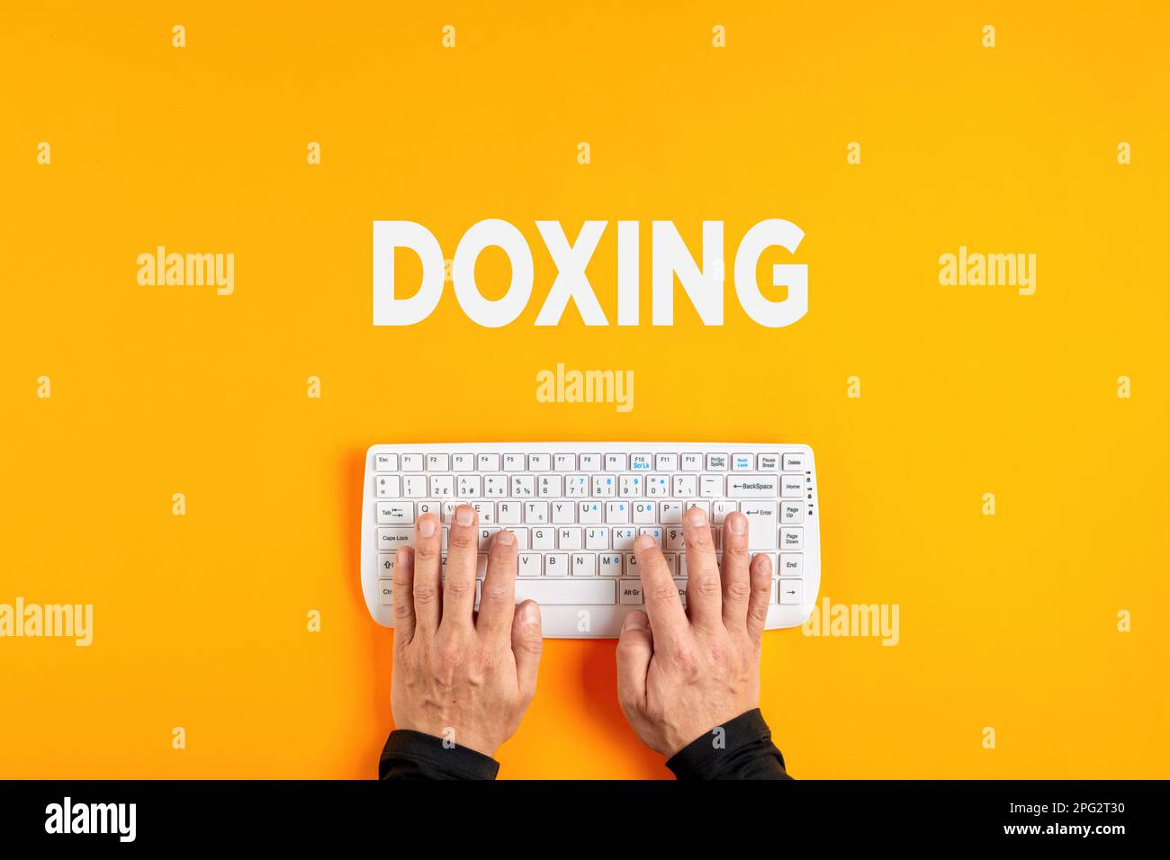 Männliche Hände, die das Wort mit einer Computertastatur eingeben. Doxing- oder Doxxing-Konzept. Stockfoto