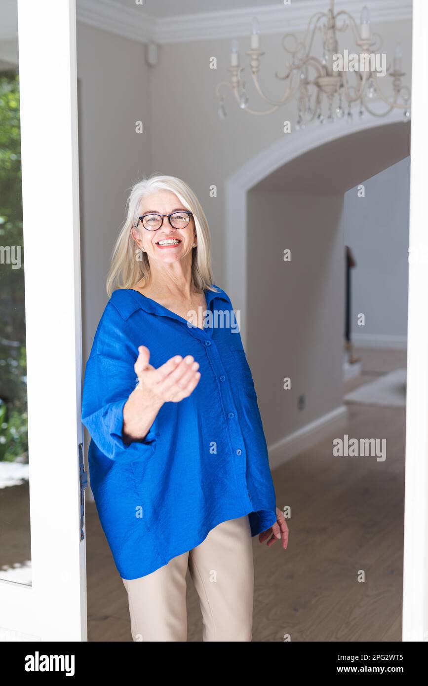 Porträt einer glücklichen weissen Seniorin, die in die Kamera schaut und an der Tür begrüßt wird Stockfoto