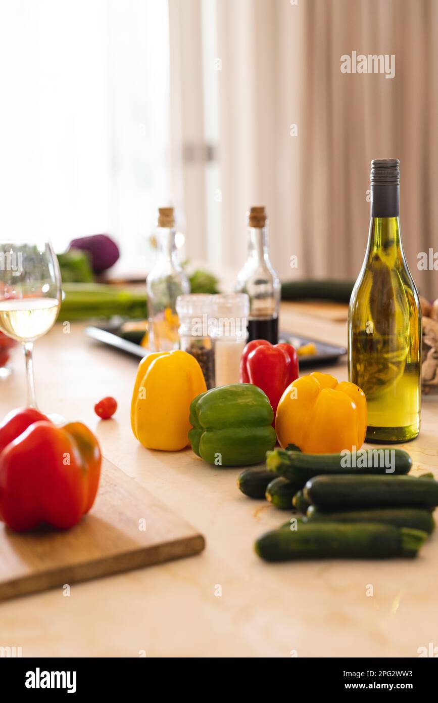 Frisches Gemüse und Gewürze auf dem Tisch in der Küche mit Flasche und Glas Weißwein Stockfoto