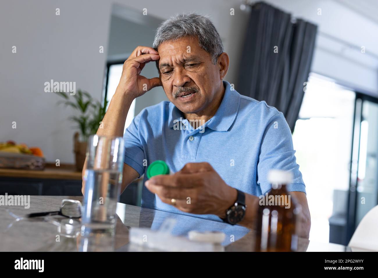 Trauriger, birassistischer Senior-Mann mit Kopf in der Hand, der zu Hause auf eine verschriebene Flasche schaut, Kopierraum Stockfoto