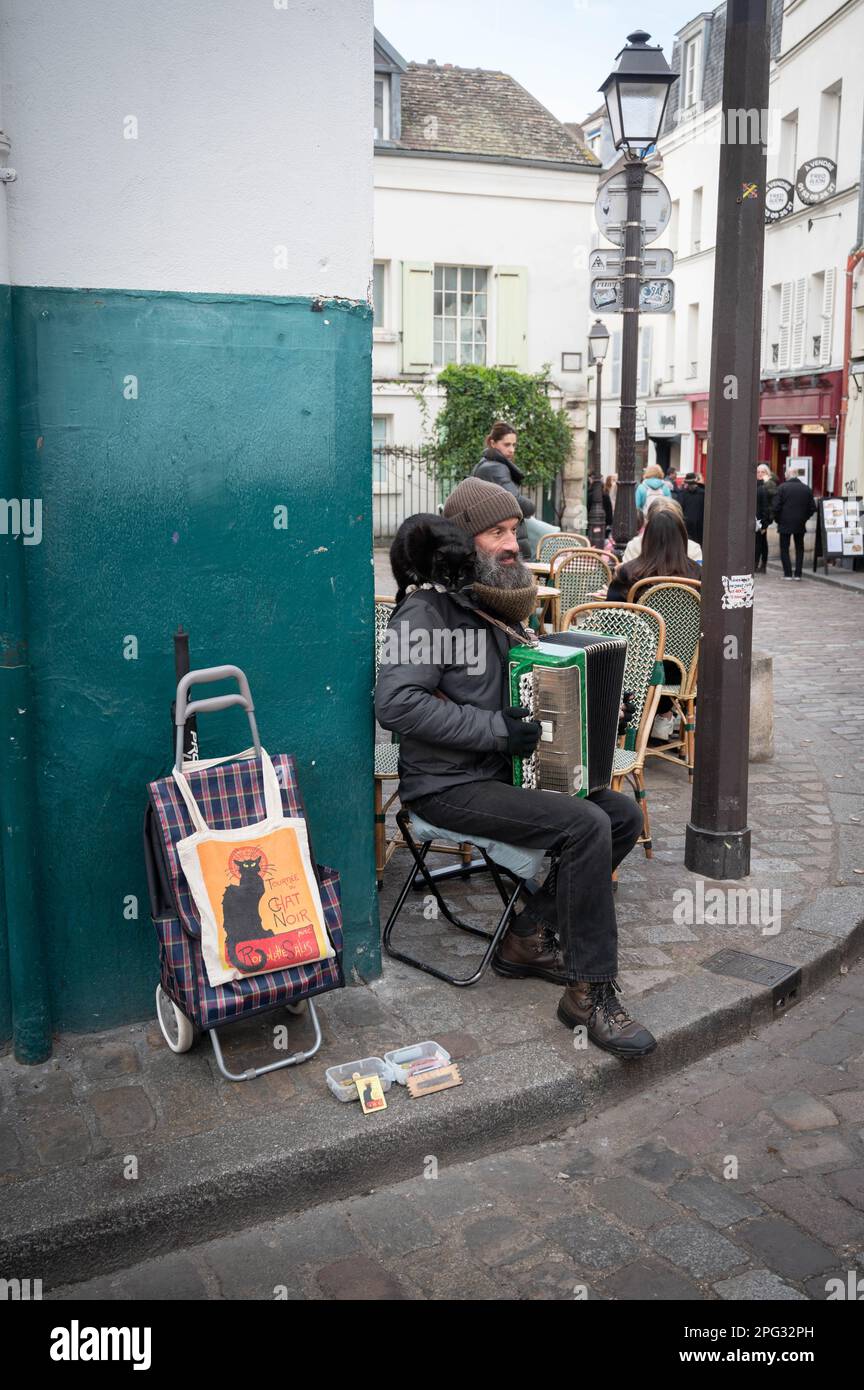 Pariser französischer Busfahrer mit Akkordeon, schwarzer Katze auf der Schulter und „Chat Noir“-Tasche, spielt auf dem Place du Tertre Artists Square in Montmartre Stockfoto