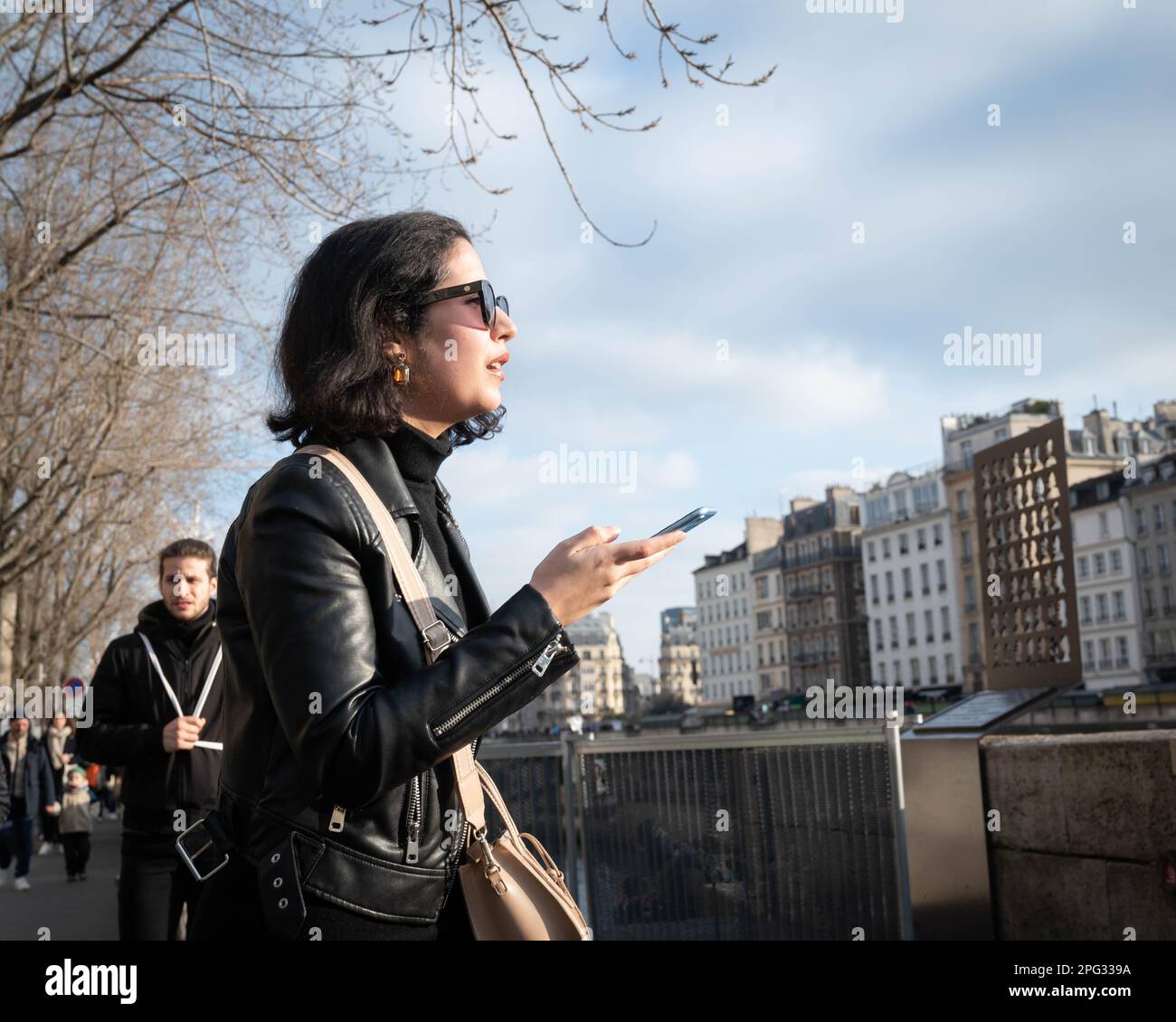 Junge Französin, die an der seine mit einem Handy in der Hand spaziert Stockfoto