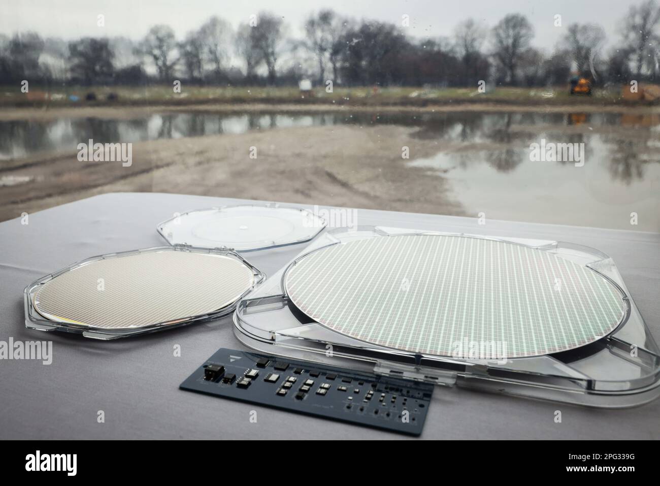 Itzehoe, Deutschland. 20. März 2023. Ein 300-Millimeter-Wafer (r) liegt neben einem kleineren Modell auf einem Tisch im Festzelt während einer bahnbrechenden Zeremonie für die neue Chip-Fabrik der Vishay Group. Der Chip-Hersteller Vishay erweitert seine Produktionsstätte in Itzehoe und plant die Schaffung von 150 neuen Arbeitsplätzen. Wafer sind Siliziumscheiben, die als Träger für die Herstellung von Mikrochips dienen. Kredit: Christian Charisius/dpa/Alamy Live News Stockfoto