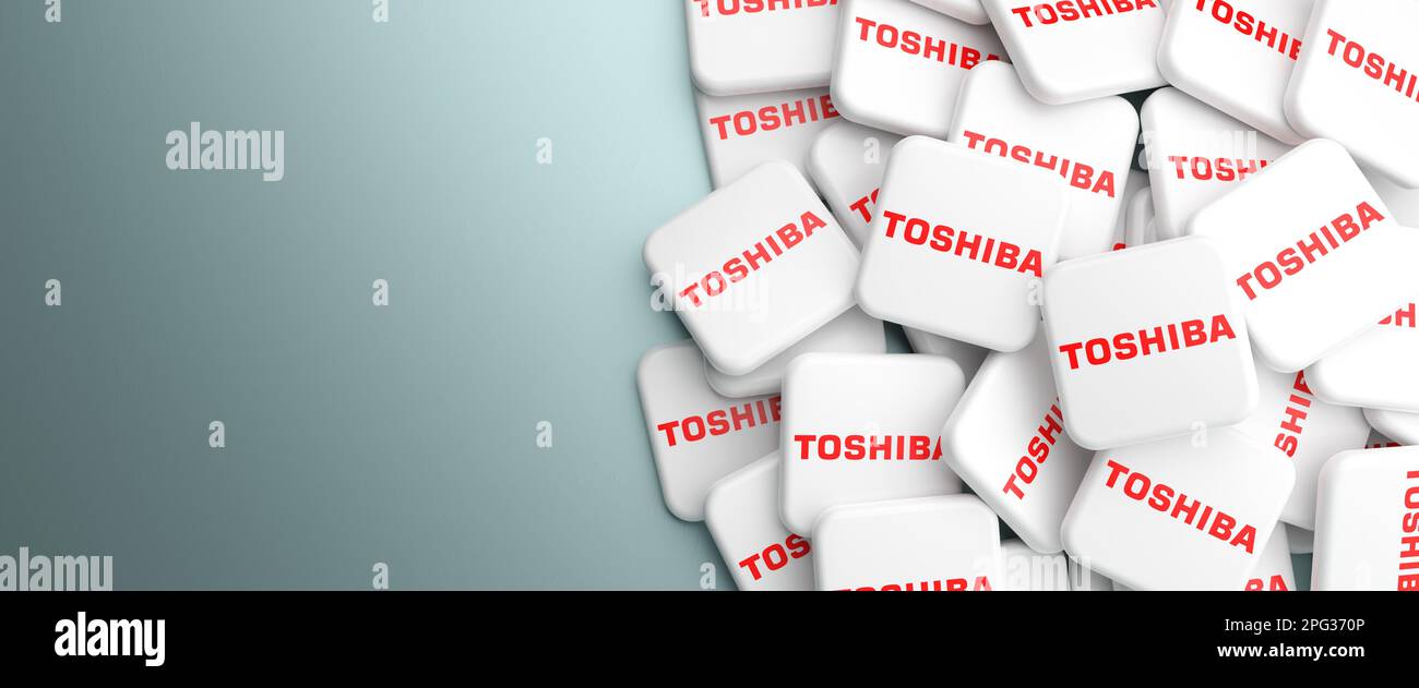 Logos des Technologieunternehmens Toshiba (Speicherlösungen, Halbleiter, Klimaanlage, Heizung) auf einem Haufen auf einem Tisch. Webbannerformat, Kopie en Stockfoto
