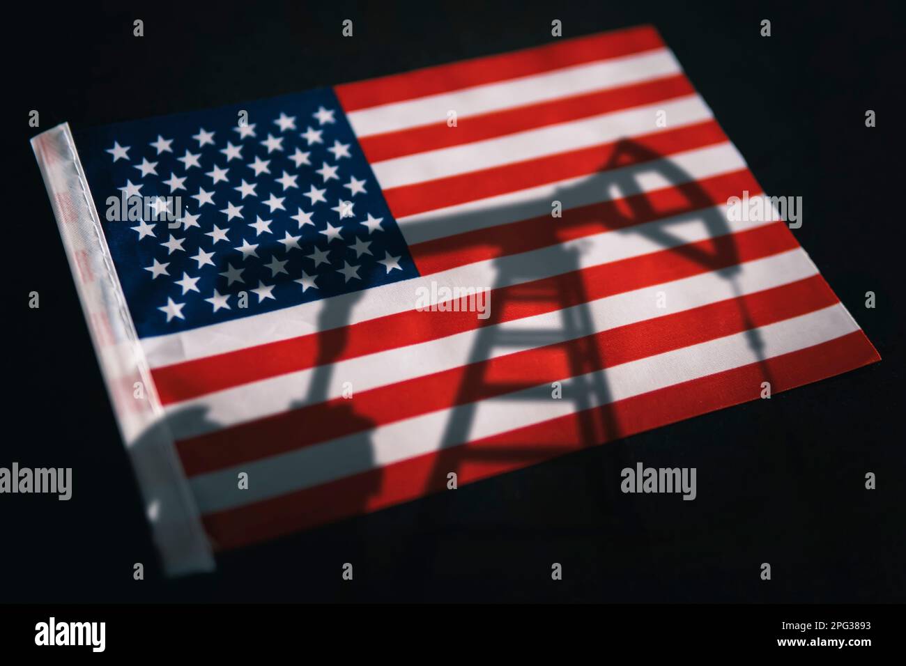 Die Ölindustrie der USA. Bohrinseln im Hintergrund der Flagge der Vereinigten Staaten von Amerika. Bergbau und Ölexport. Handel auf dem globalen Kraftstoffmarkt. Kraftstoff i Stockfoto