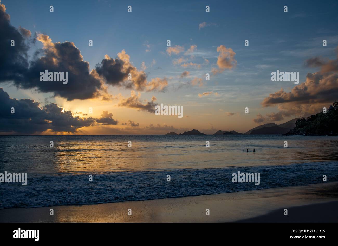 Sonnenuntergang mit zwei schwimmenden Personen Anse Louis Westküste Mahe Seychellen Stockfoto