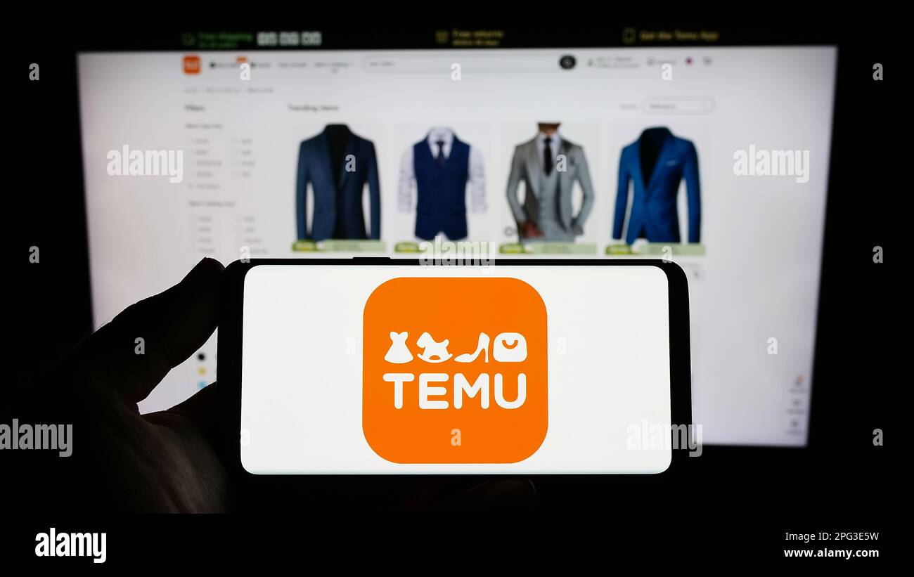 Person, die ein Smartphone mit dem Logo des US-amerikanischen Online-Shop-Unternehmens Temu auf dem Bildschirm vor der Website hält. Konzentrieren Sie sich auf das Display des Telefons. Stockfoto