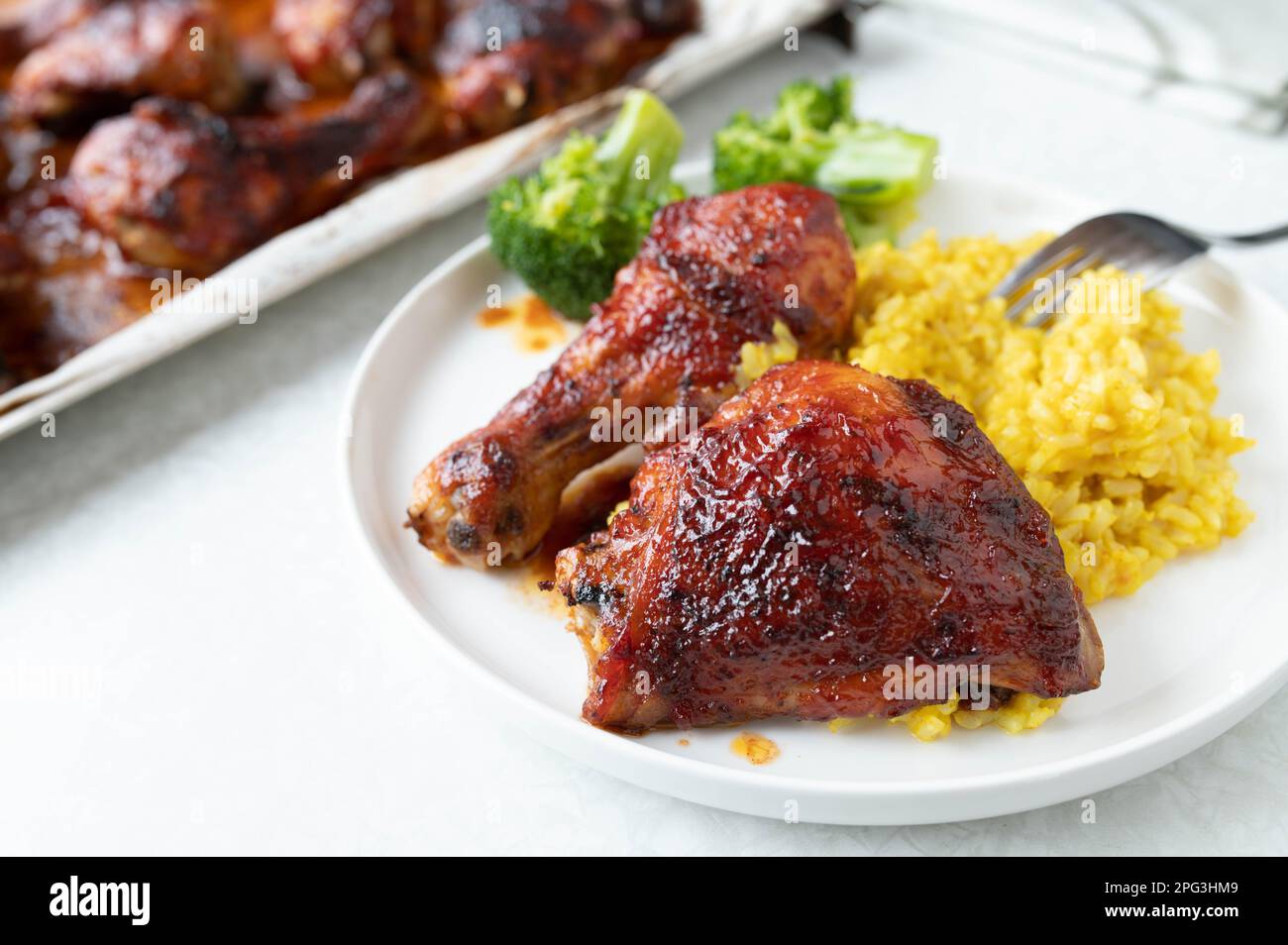Glasiertes Huhn mit Pilaureis und Brokkoli auf einem Teller Stockfoto