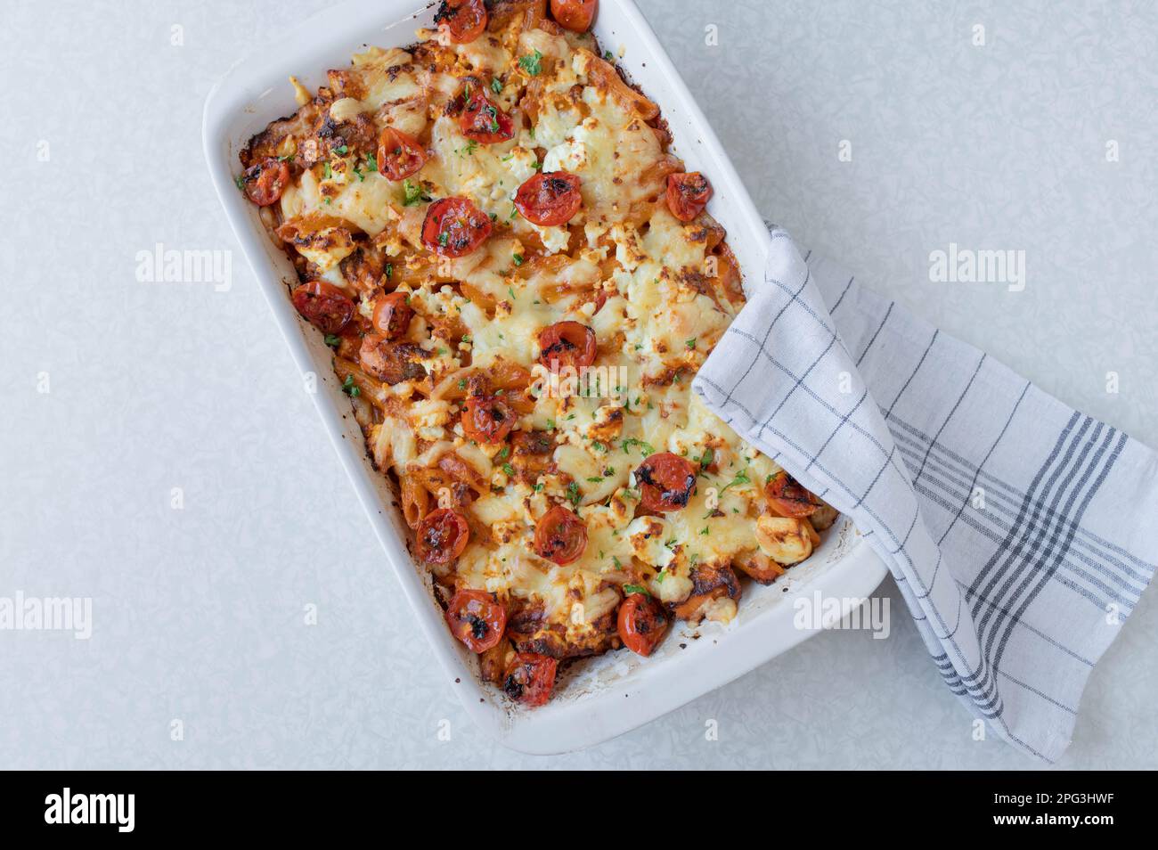 Fischauflauf mit Lachs, Pasta, Tomaten, Sahne und Käse in einem weißen Auflauf, isoliert auf weißem Hintergrund Stockfoto