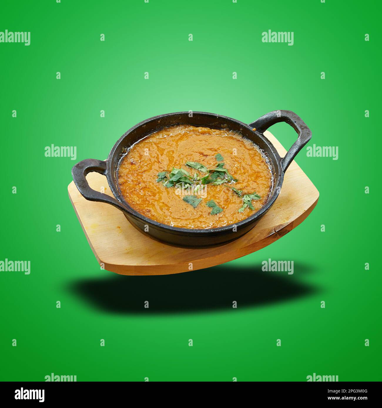 Schwimmender Dhal in einer kleinen Pfanne auf grünem Hintergrund gebacken Stockfoto
