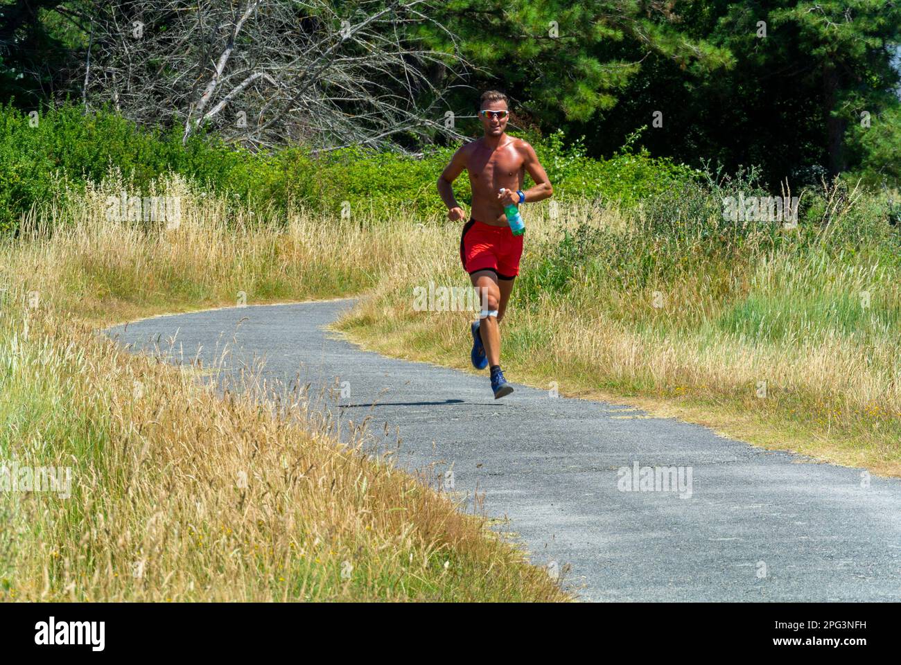 Ile d'Arz, Frankreich, Bretagne, Mann beim Joggen auf der Country Road Stockfoto