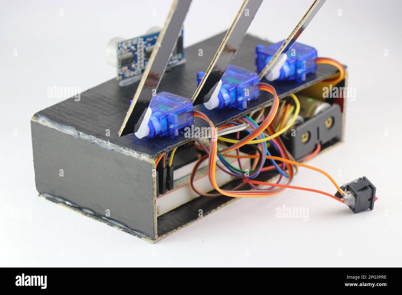 Mikro-Servos oder Servomotoren aus Kunststoff sind über Überbrückungsdrähte in einem interaktiven Elektronikprojekt mit einer Steckplatine und einem Mikrocontroller verbunden Stockfoto
