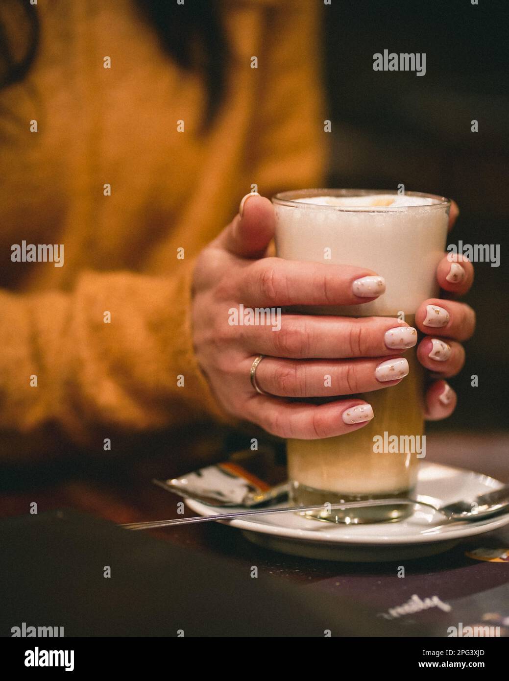 Eine Frau, die eine Tasse frisch zubereiteten, warmen Kaffee mit Schaum in der Hand hält Stockfoto