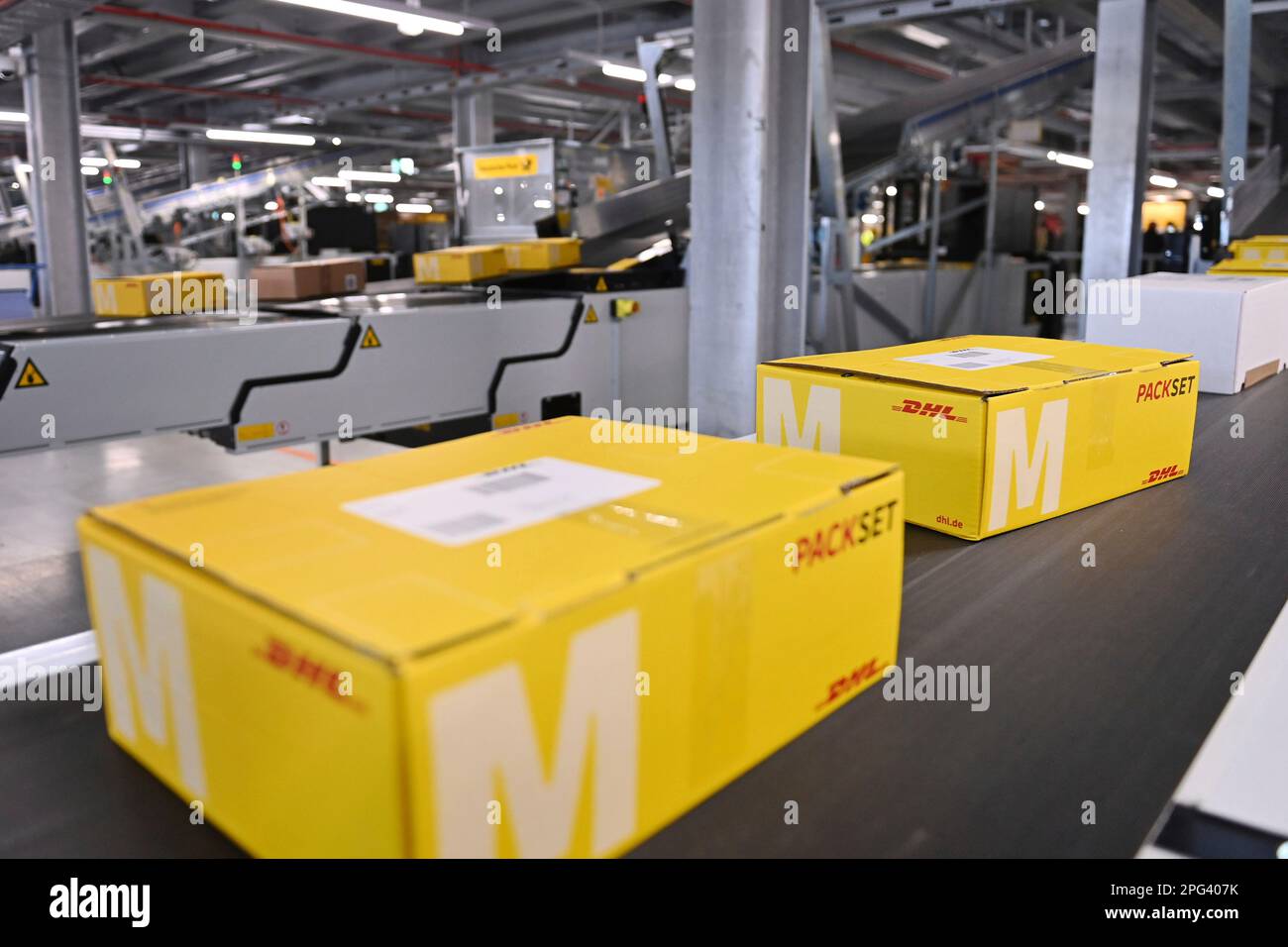 Deutsche Post DHL nimmt am 20. März 2023 den größten Paketstandort Deutschlands in Betrieb. Bearbeitung von bis zu 72.000 Paketen pro Stunde im Aschheim II-Paketzentrum bei München. Paket, Pakete auf Bändern, Förderband, Förderbänder? Stockfoto