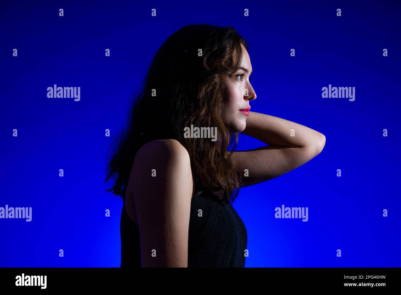 Nahaufnahme von der Seite des Teenage Girl im Profil vor dem königsblauen Hintergrund Stockfoto