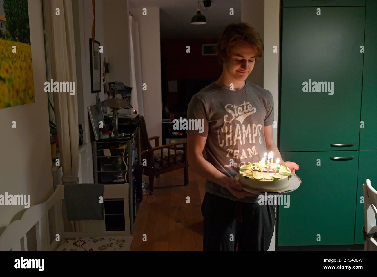 Teenager von 17 mit Geburtstagskerzen-Kuchen zu Hause Stockfoto