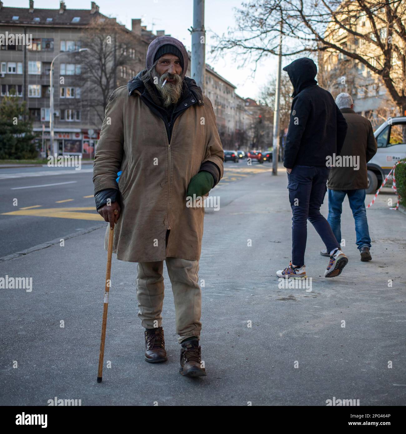 Belgrad, Serbien, 18. März 2023: Ein bärtiger Mann läuft mit einem Gehstock die Straße hinunter Stockfoto