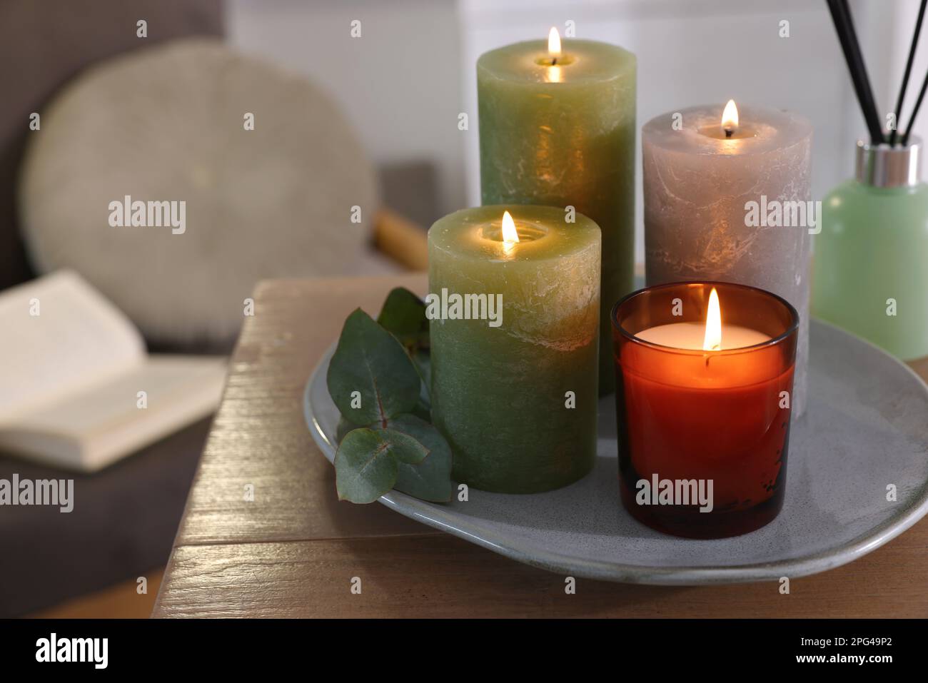 Schöne brennende Kerzen und Lufterfrischer auf Holztisch im Innenbereich, Platz für Text Stockfoto