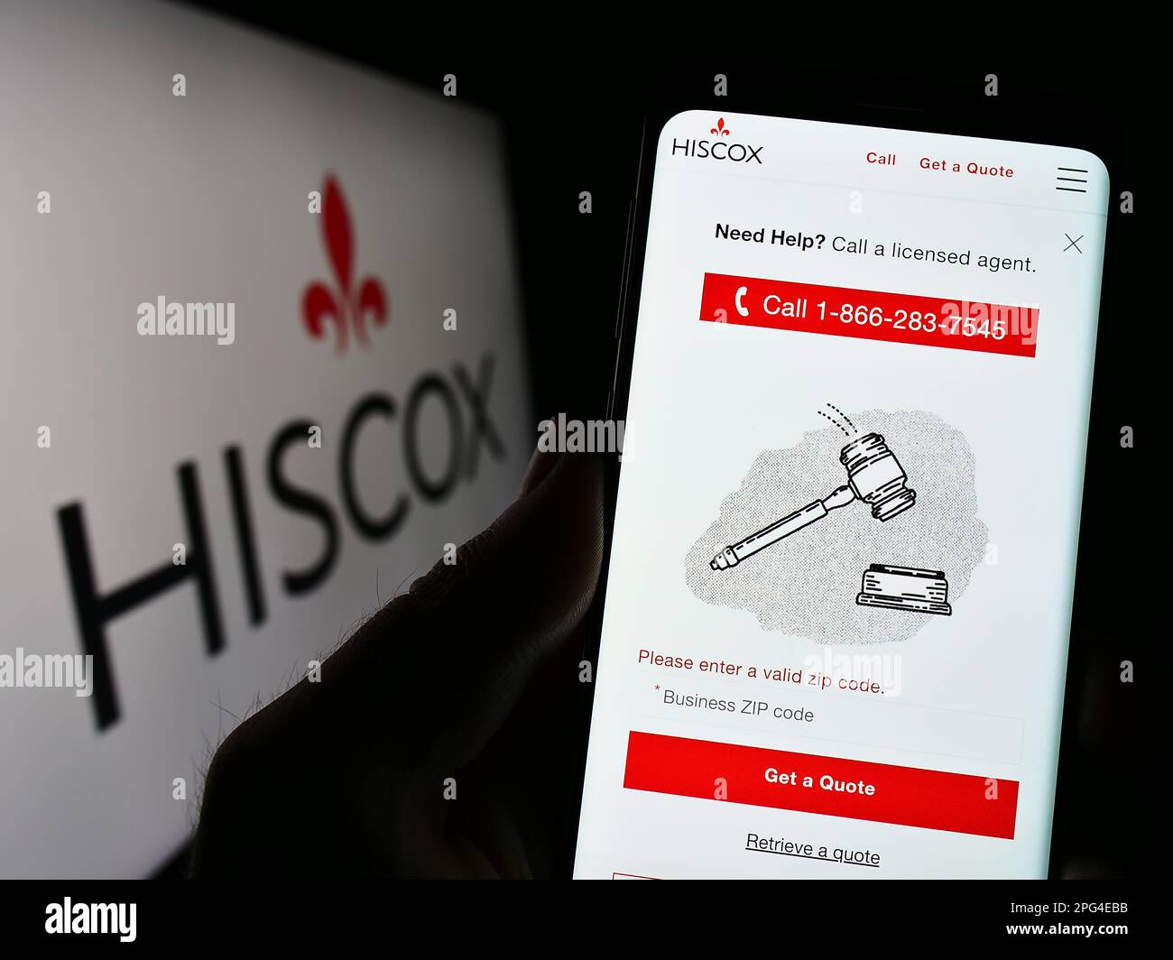 Person mit Smartphone und Webseite der Versicherungsgesellschaft Hiscox Ltd. Auf dem Bildschirm vor dem Unternehmenslogo. Konzentrieren Sie sich auf die Mitte des Telefondisplays. Stockfoto