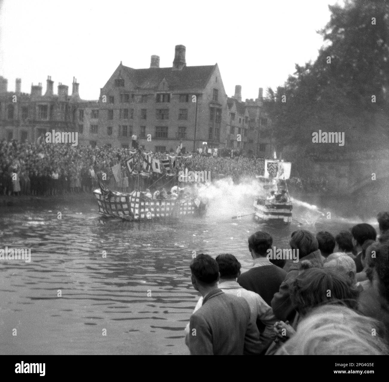 1950er Jahre, historisch, Cambridge University, große Anzahl von Menschen am Flussufer des Flusses Cam, die ein Boot-Duell beobachten. Während der Rag Week, Cambridge, England, UK....eine Nachstellung der 'Schlacht von Trafalgar. Stockfoto
