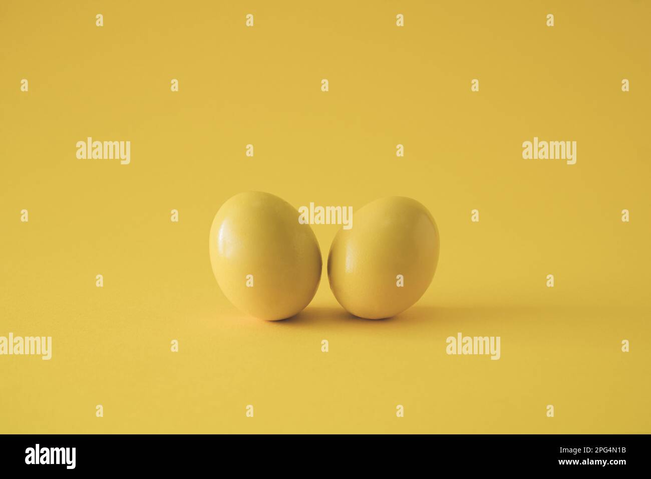 Zwei gelbe Eier auf gelbem Hintergrund. Minimales Osterkonzept. Stockfoto
