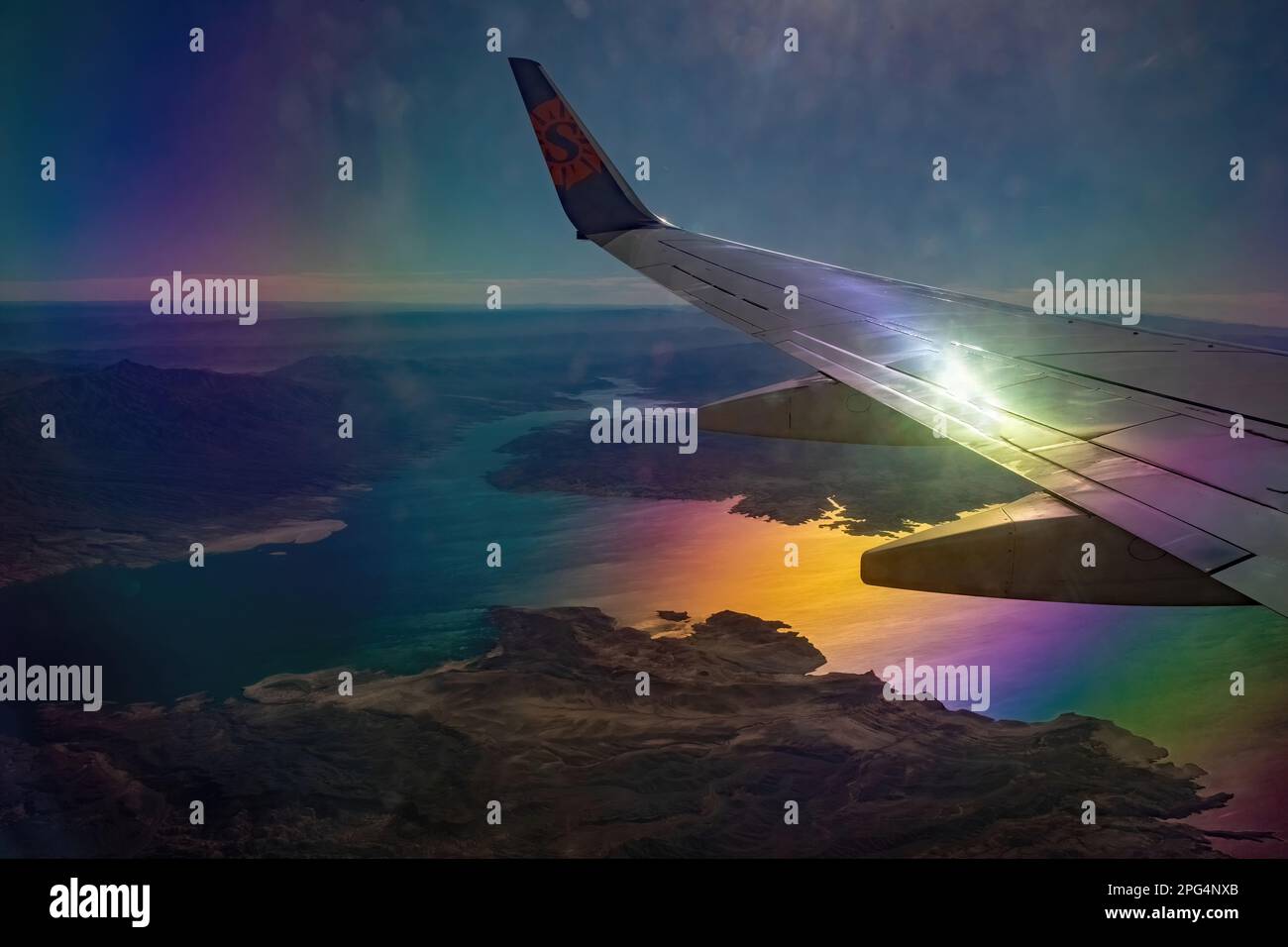 Sun Countries Airlines Flugzeug Flug hoch über die Berge und Hügel von Colorado mit dem Sonnenlicht, das vom Flugzeug und vom Wasser reflektiert wird. Stockfoto