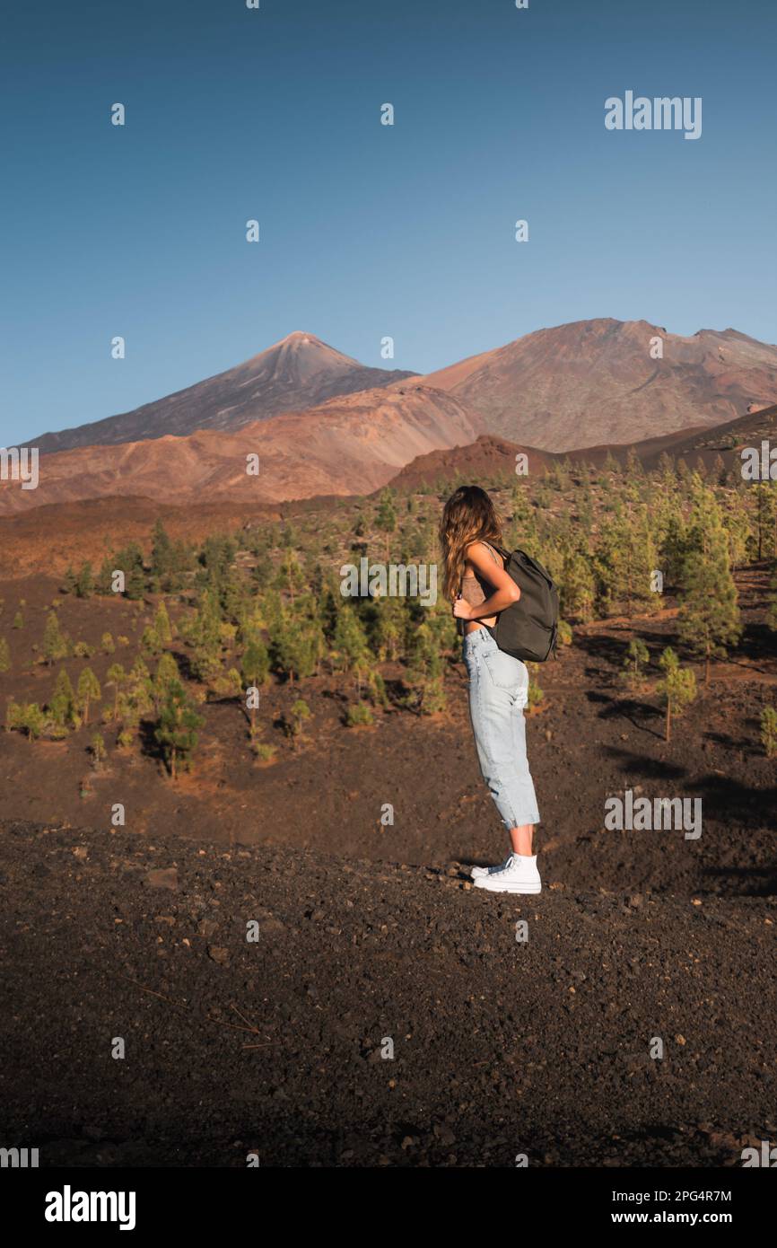 Chica con mochila contemplando el pico Teide mientras hace una ruta de senderismo en Teneriffa. Stockfoto
