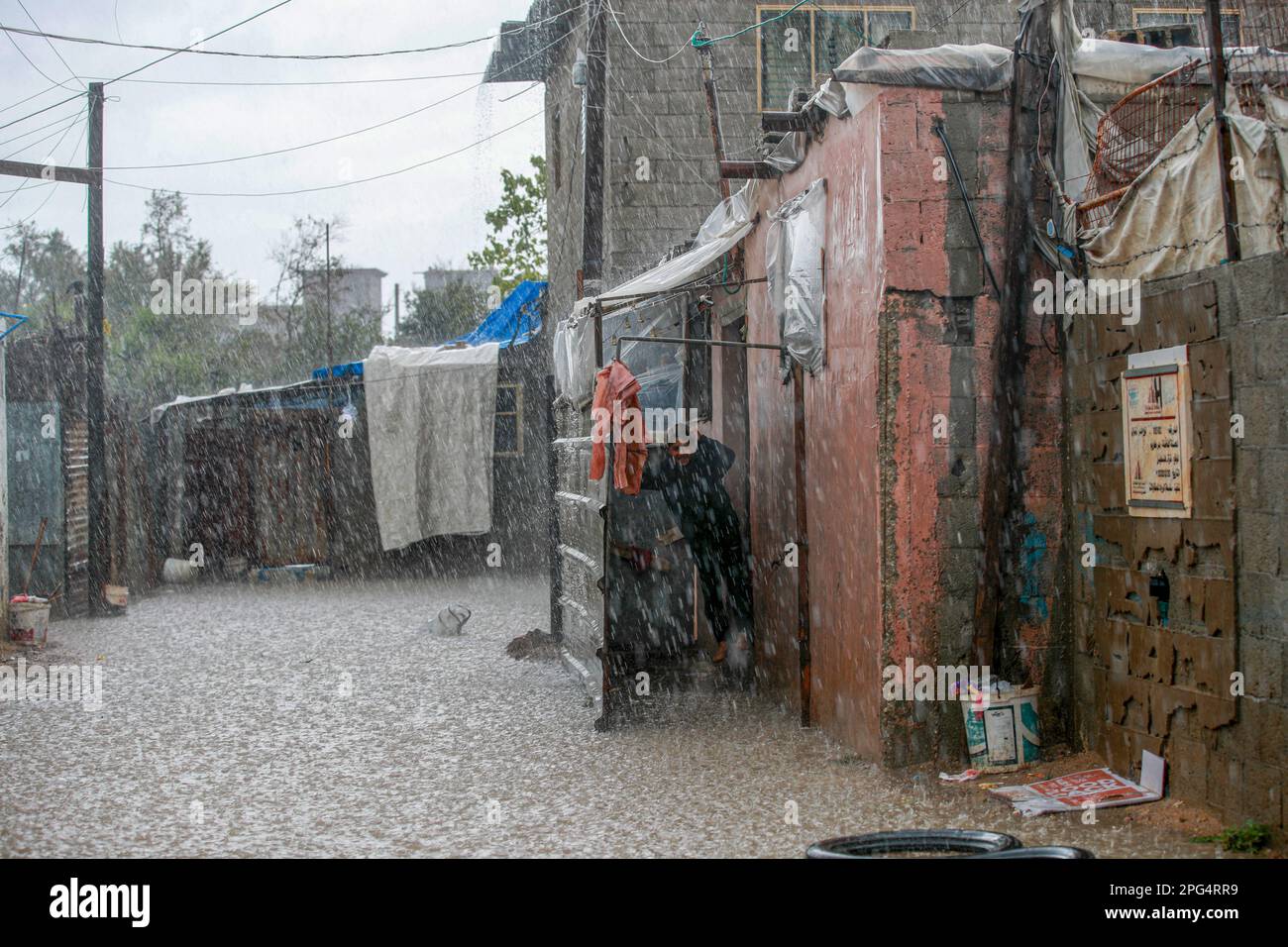 Gaza-Stadt, Palästina. 20. März 2023 Die Palästinenser gehen in Lahiya, nördlich von Gaza City, durch eine mit Regenwasser überflutete Straße. Stockfoto