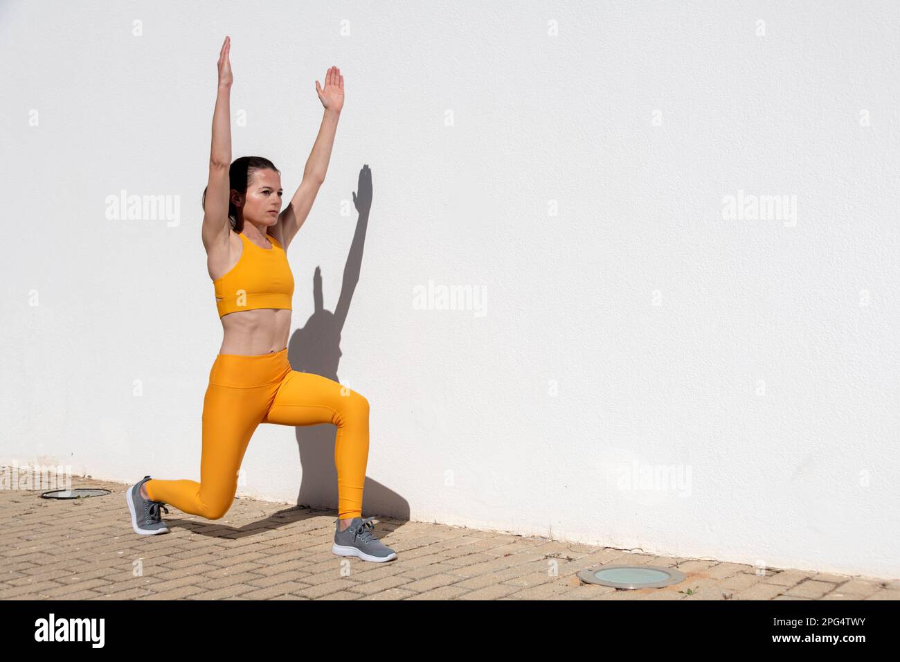 Sportliche Frau, die im Freien in der Sonne Ausfallschritte macht Stockfoto