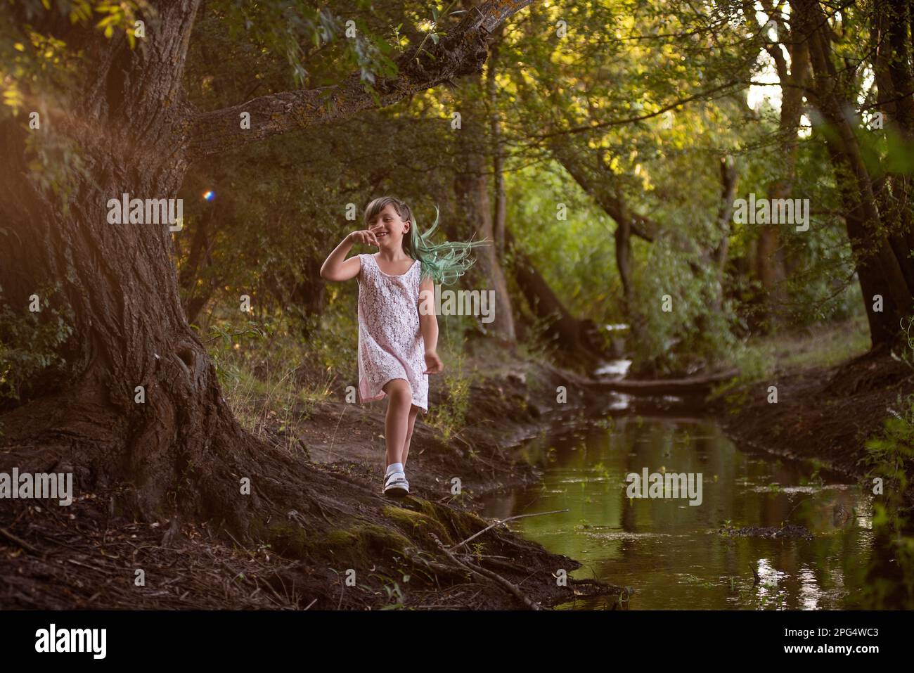 Teenager-Mädchen haben Spaß, machen in der Nähe des kleinen Flusses, des Flusses herum. Diversität, Kind der Z-Generation mit grünem Haar in der Nähe von Wasser im Wald. Konzept der Freiheit, Stockfoto
