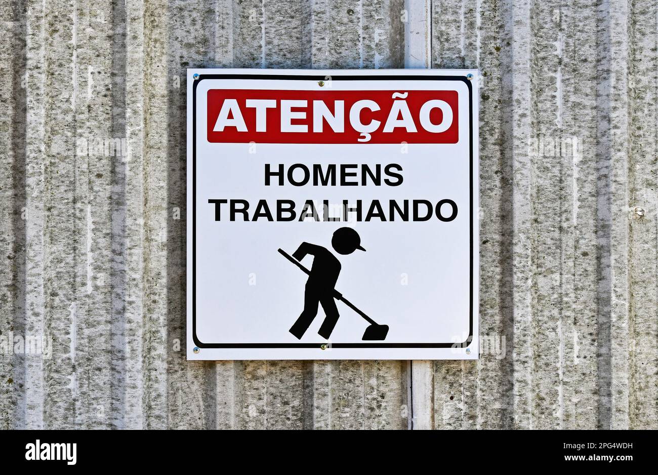 Metallschild auf portugiesische Wörter, das MÄNNER BEI DER ARBEIT anzeigt Stockfoto