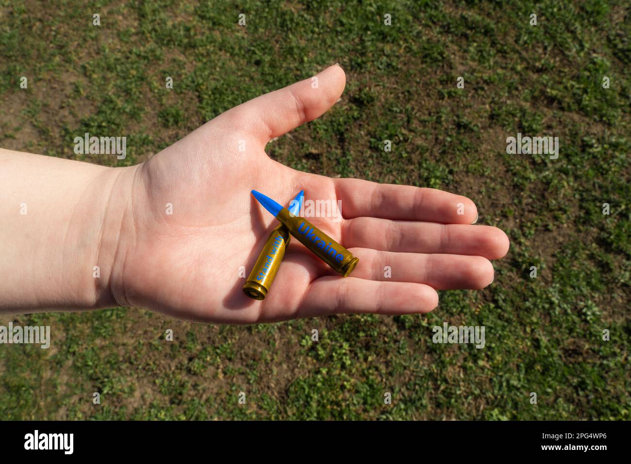 Zwei gelbblaue Gewehrkassetten mit AUFKLEBERSTAND MIT UKRAINE in der Hand (nationale Symbole der Ukraine). Konzept der militärischen Unterstützung für die Ukraine Stockfoto