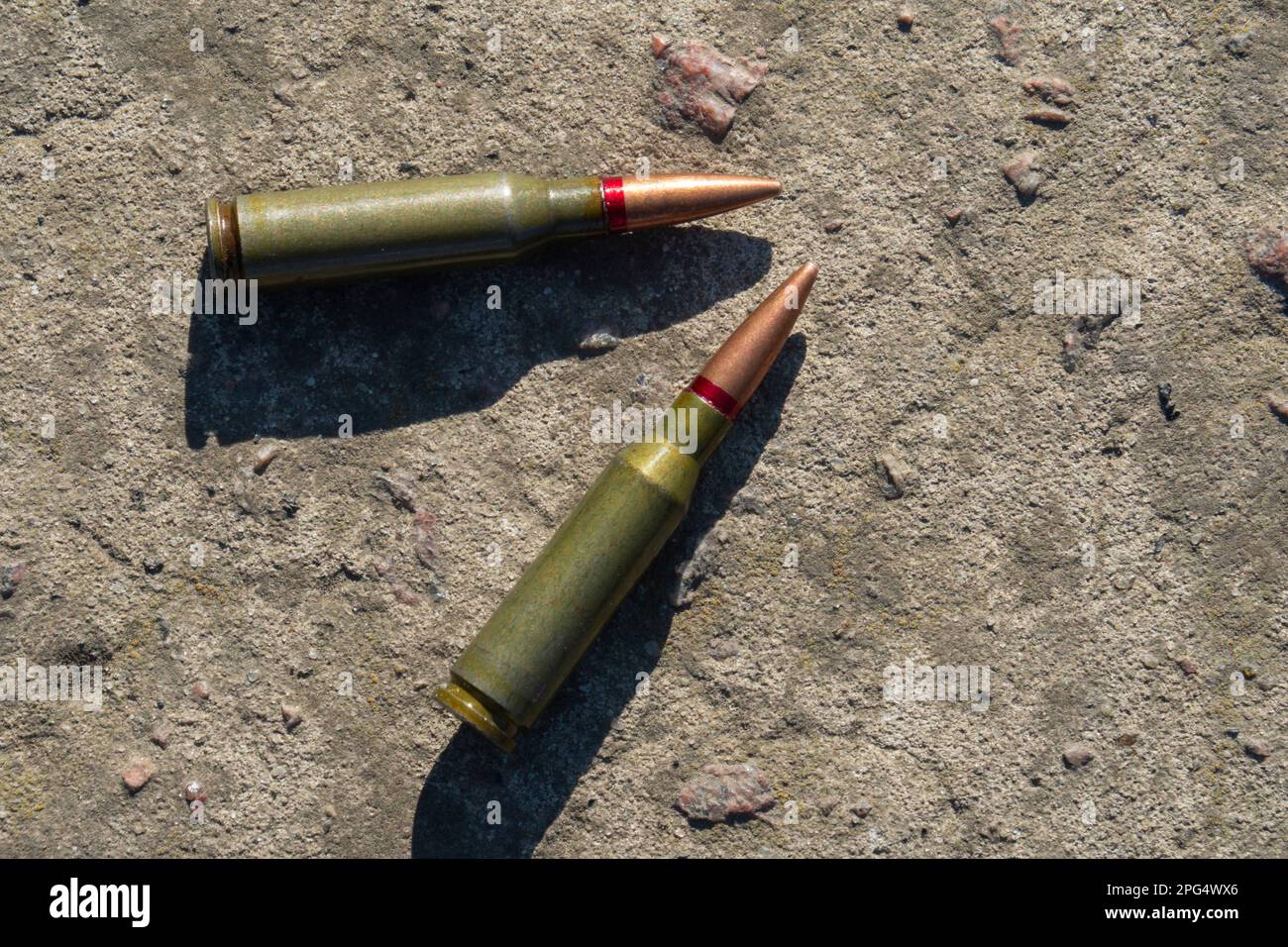 Zwei Kartuschen für Gewehre liegen auf einer Betonoberfläche (Nahaufnahme) Stockfoto