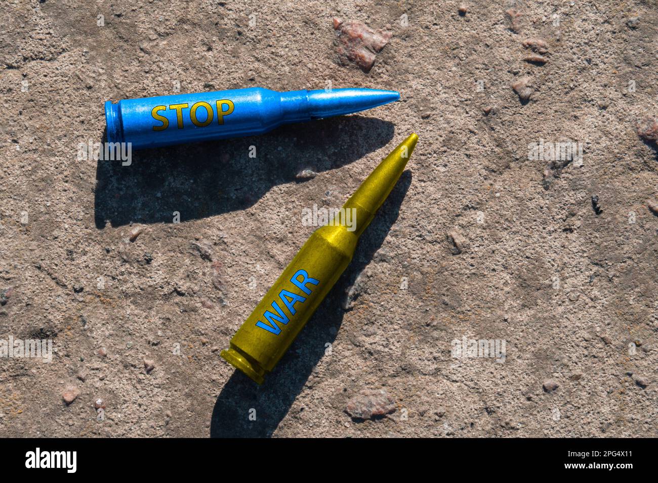 Gelbe und blaue Kartuschen mit der Aufschrift STOP WAR liegen auf einer Betonoberfläche (Nahaufnahme). Das Konzept der militärischen Unterstützung für die Ukraine Stockfoto