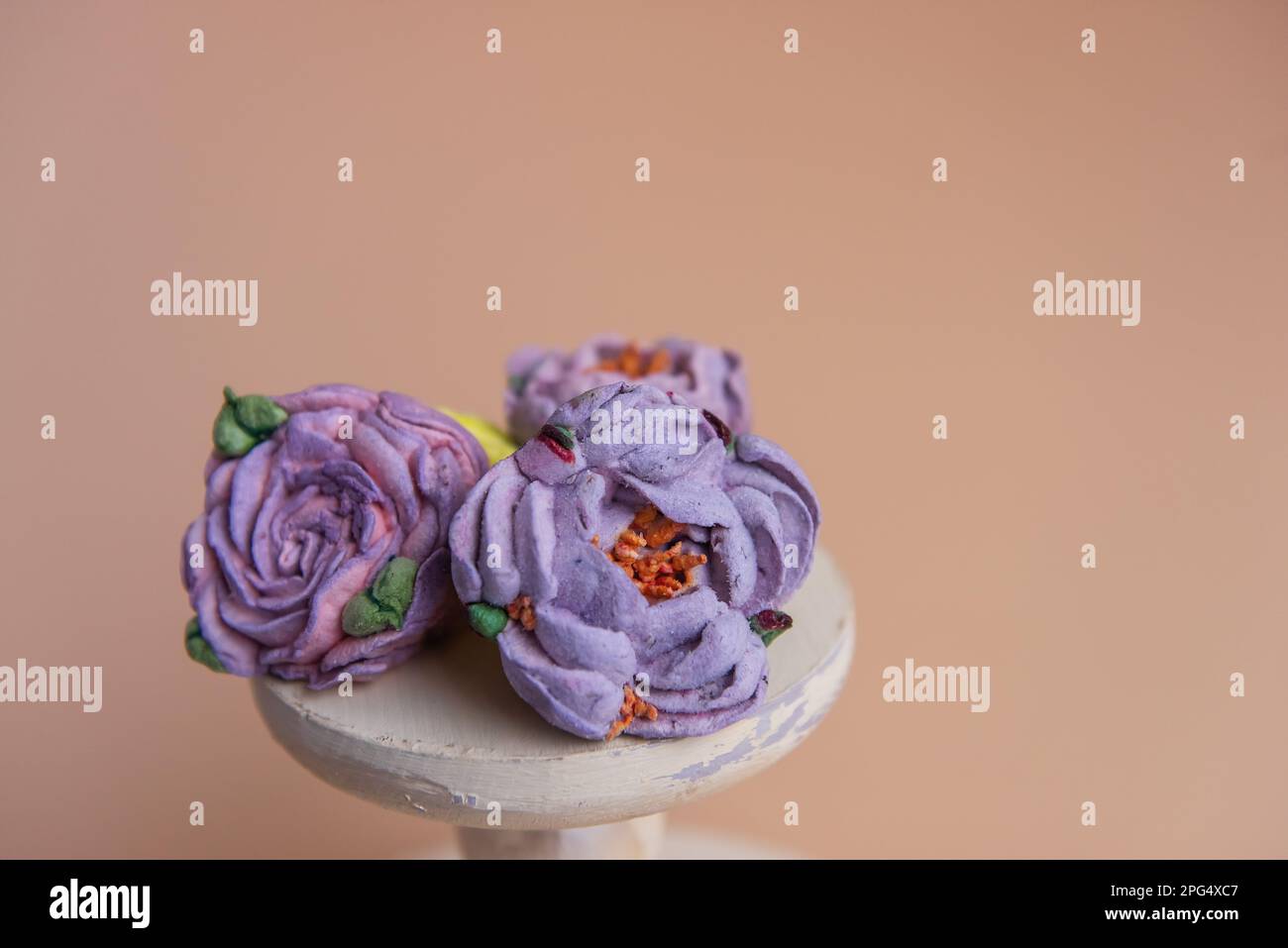 Auf einem runden Holzhintergrund liegen natürliche Marshmallows in Form von violetten Pfingstrosen. Süße Desserts ohne Zucker. Kreative Backwaren. Stockfoto