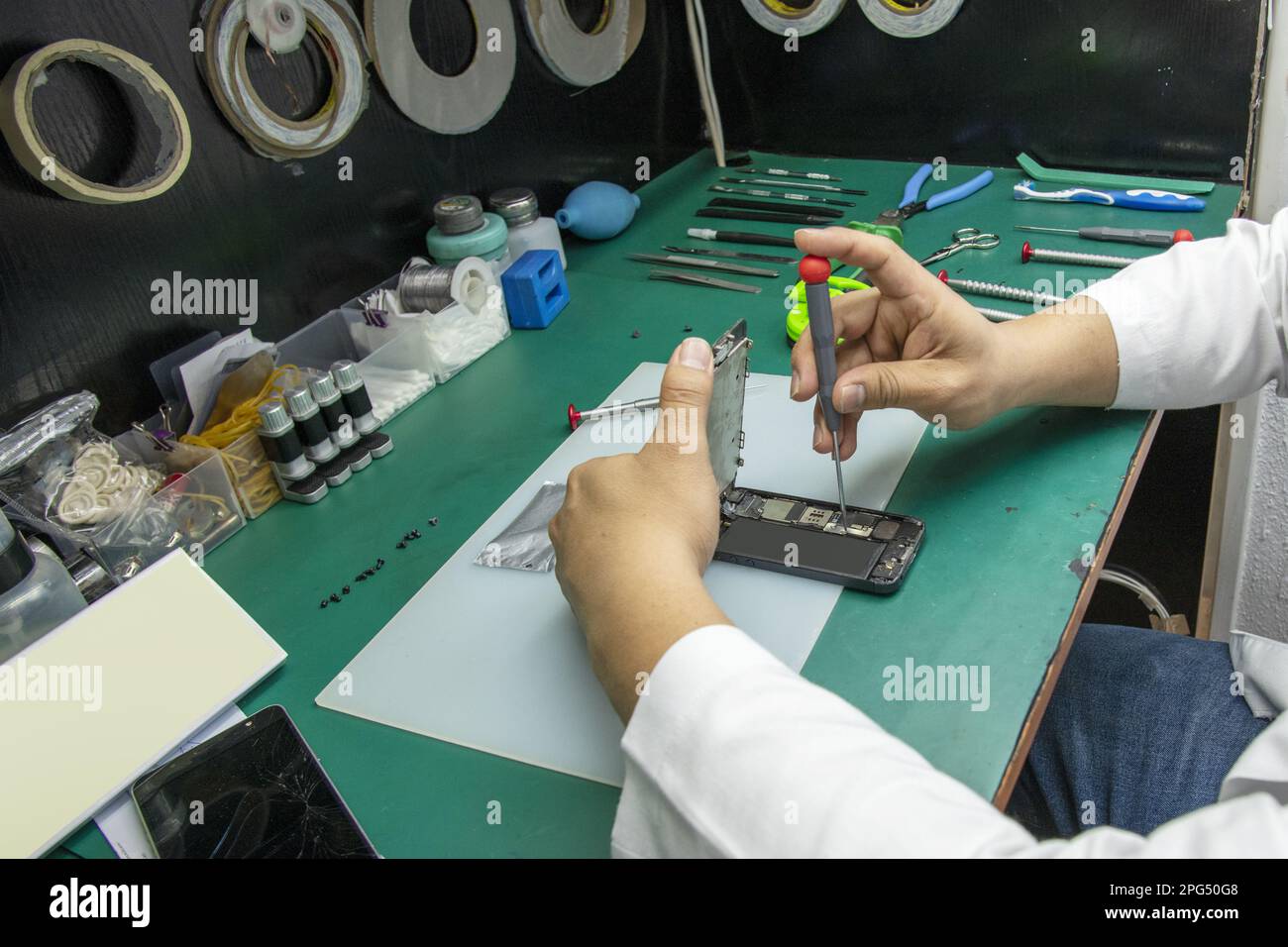 Ein Techniker, der ein Mobiltelefon in seinem kleinen, größeren zerlegt Stockfoto