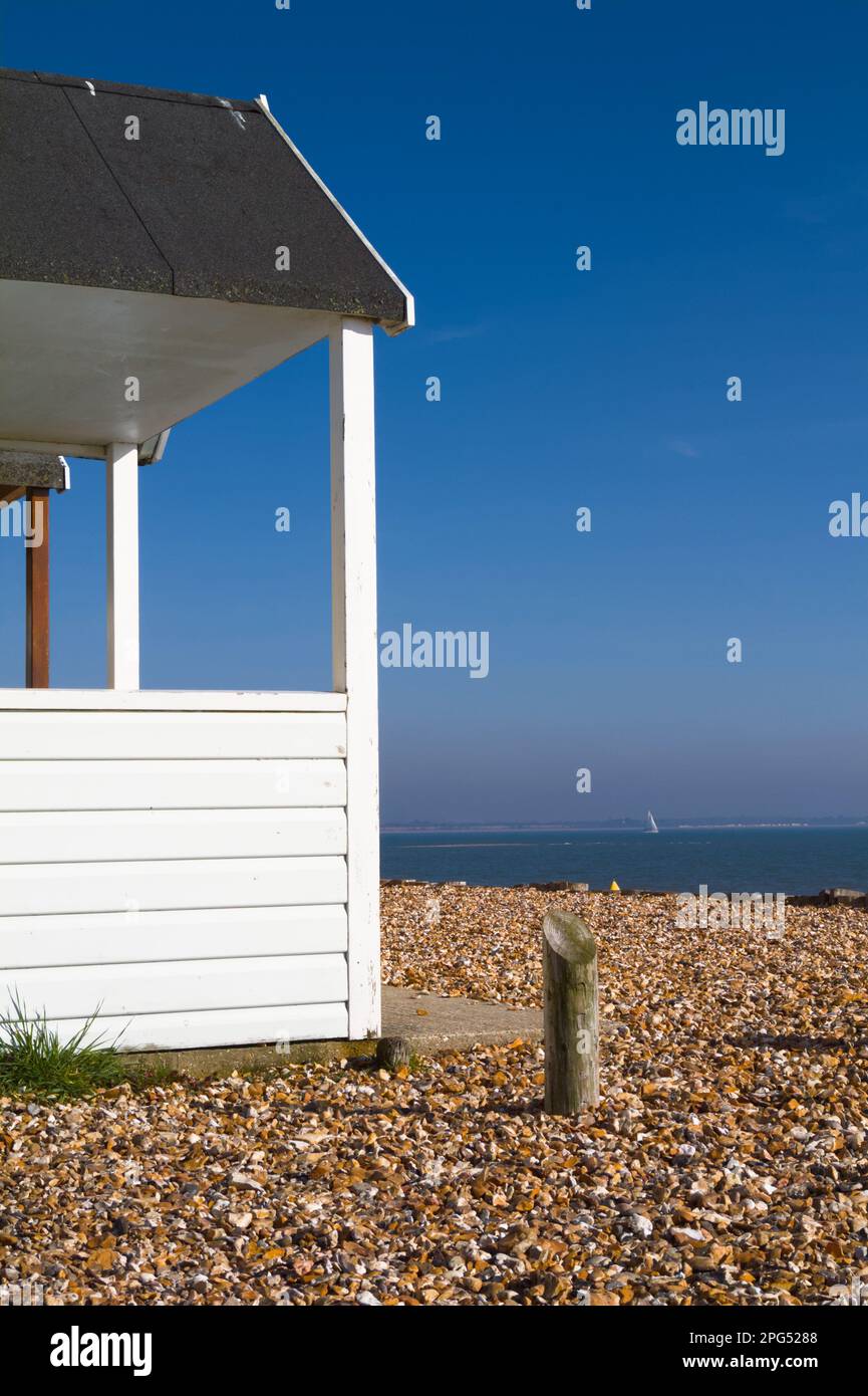 Beach Hut auf Shingle Calshot Beach mit Segelschiff auf Solent im Hintergrund, Calshot UK Stockfoto