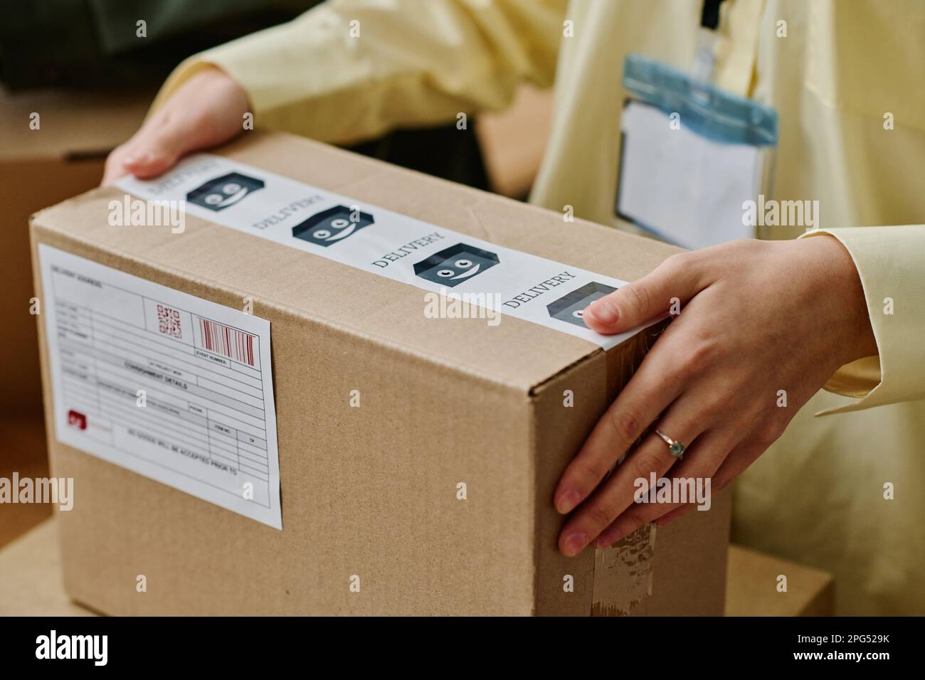 Hände einer jungen Freiwilligen mit verpackten Pappkartons mit Kleidung oder anderen Spenden für Menschen, die in einer Krise stecken Stockfoto