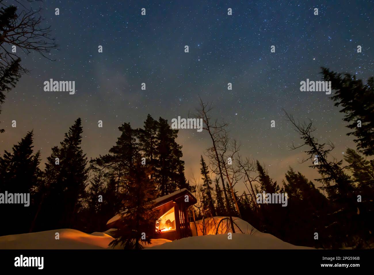 Sterne über einer abgelegenen Hütte im Schnee in einem Wald in Norwegen Stockfoto