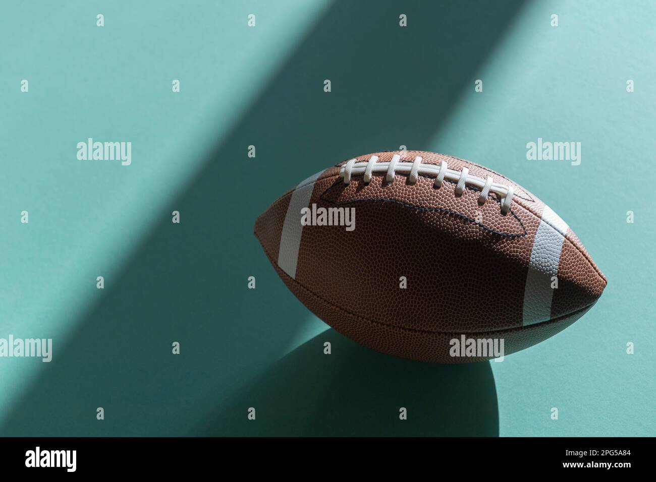 American Football-Lederball mit mintfarbenem Hintergrund. Draufsicht. Spielausrüstung horizontales Sportposter, Grußkarten, Kopfzeilen, Website und Stockfoto