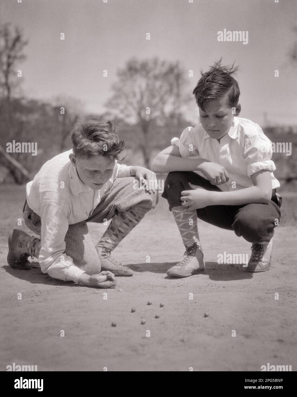 1920S 1930S ZWEI JUNGEN KNIEN IN MARMOR UND TRAGEN SLIP-HOSEN, HOHE GEMUSTERTE SOCKEN UND HI TOP SPEEDSTER-SCHUHE - B6983 HAR001 HARS ERSCHIESSEN MÄNNLICHE GESCHWISTER B&W KNIEND MURMELN HOCHWINKEL ABENTEUER FREIZEIT UND AUFREGENDE ERHOLUNG GESCHWISTER HI FRIENDLY KNUCKLE DAUNEN STILVOLLE KURZE HOSEN GEMUSTERT WACHSEN JUGENDLICHE JUGENDLICHE JUGENDLICHE JUGENDLICHE JUGENDLICHE JUGENDLICHE JUGENDLICHE JUGENDLICHE JUGENDLICHE ZUSAMMENGEHÖRIGKEIT SCHWARZ-WEISS WEISSE ETHNISCHE ZUGEHÖRIGKEIT HAR001 KNIEND ALTMODISCH Stockfoto