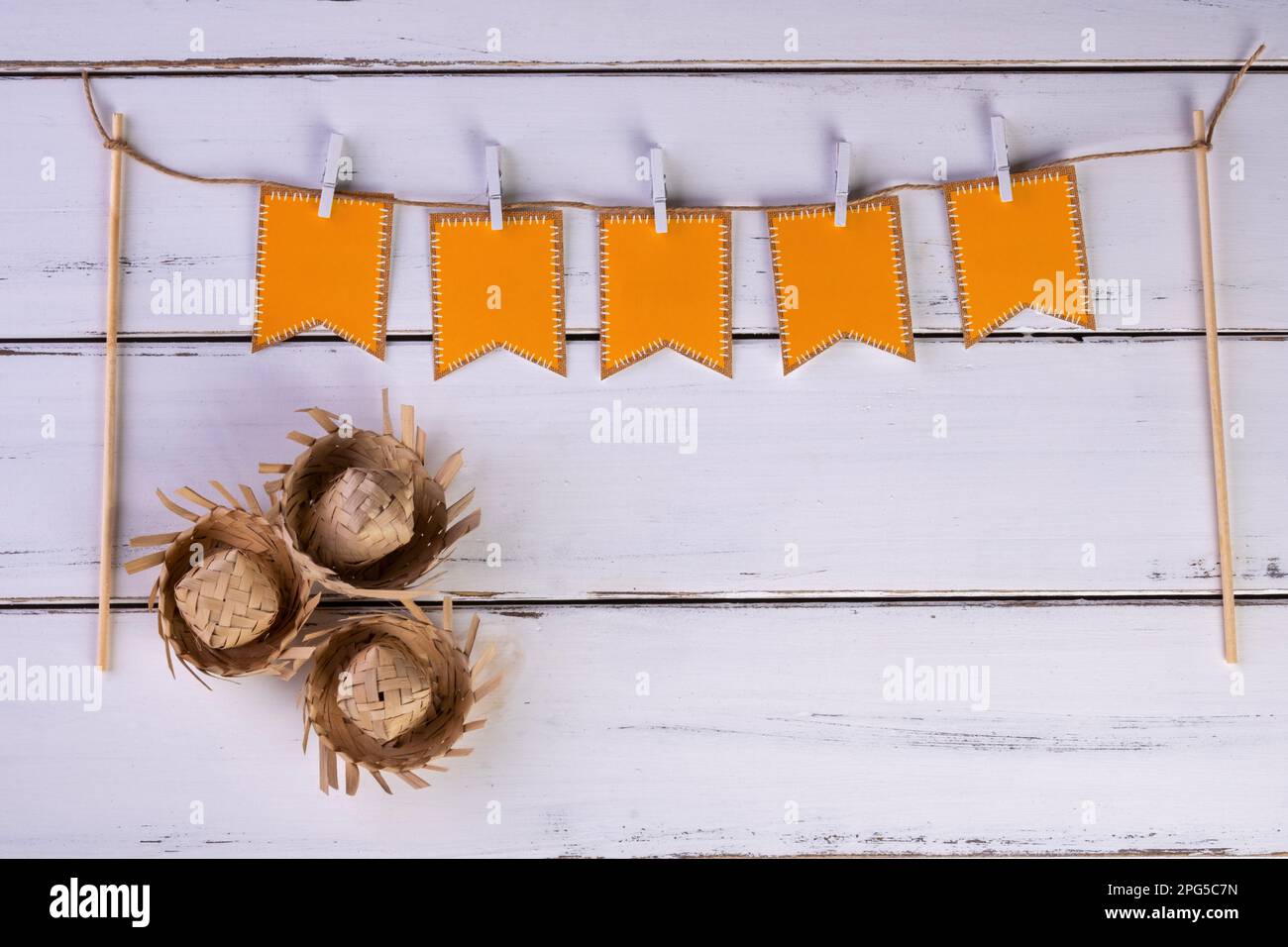 Wäscheleine mit Partyflaggen und Strohhüten auf weißem Holztisch. Stockfoto