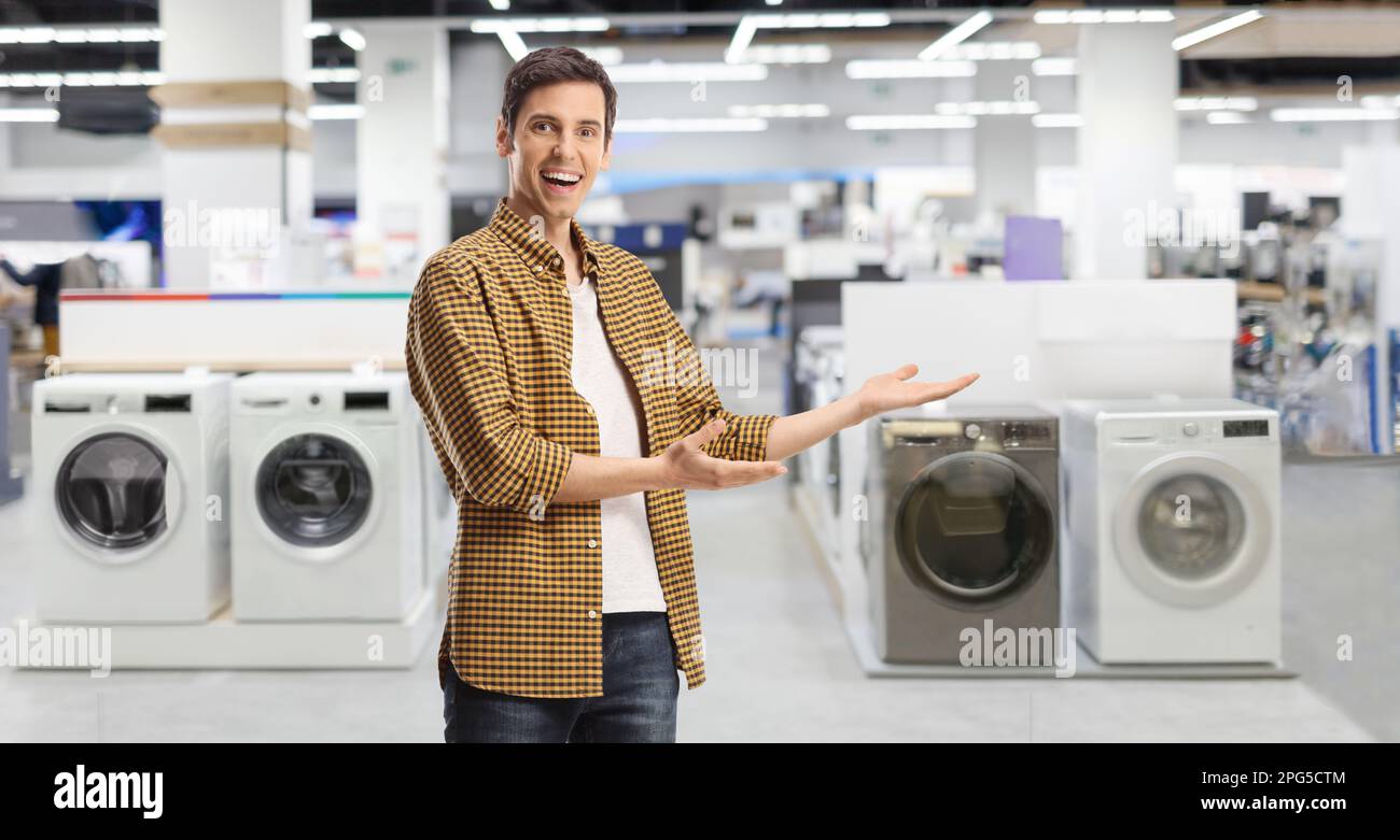Ein junger Gelegenheitsmann präsentiert ein Elektrogerätehaus mit Waschmaschinen Stockfoto