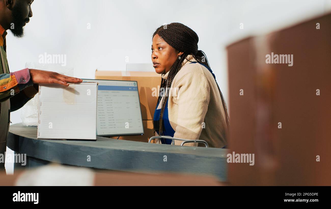 Lagerarbeiter planen Lagerlogistik per Computer und arbeiten mit Produkten in Kartonverpackungen im Lager. Frau, die im Lagerraum mit Waren und Paketen arbeitet. Stockfoto