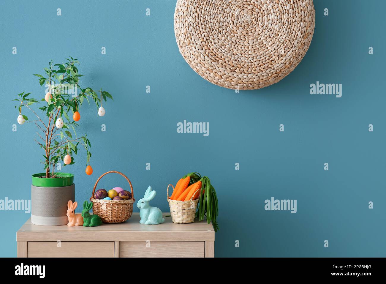 Osterdekorationen auf einem Holzschrank in der Nähe der blauen Wand Stockfoto