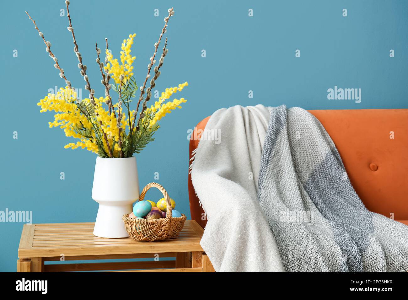 Blumenvase und Korb mit bemalten Eiern auf dem Tisch im Wohnzimmer Stockfoto