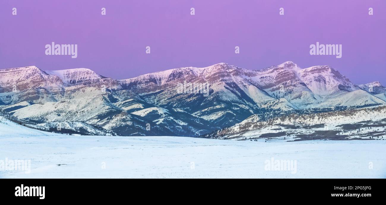 Panoramablick über den Himmel vor der Dämmerung über dem Dampfbootberg entlang der felsigen Bergfront im Winter bei augusta, montana Stockfoto