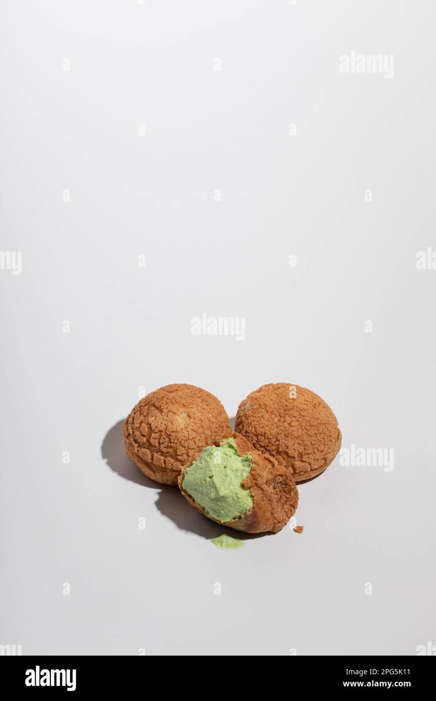Drei Matcha Cream Puffs mit einem Bissen auf grauem Hintergrund Stockfoto